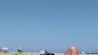 She masturbates her on the naturist beach in public with a voyeur who passes by