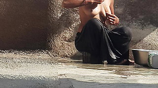 Indian sister-in-law is bathing in the open courtyard of the house, putting a finger in her burrow and rubbing the body, sister-in-law is washing the bathroom.