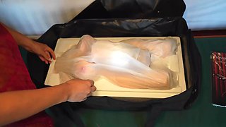 A couple has unboxed a new sex doll and is using it for sex.