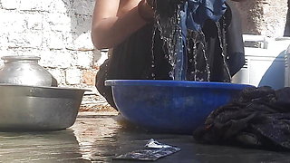 Indian stepsister is preparing to take a bath while washing clothes in the open courtyard of the house