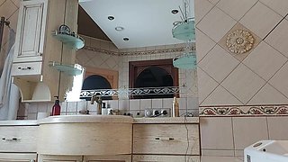 A Charming Woman Is Preening in the Bathroom in Front of a Mirror